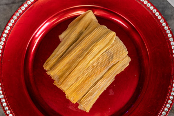 Red tray of best tamales in texas with festive background.