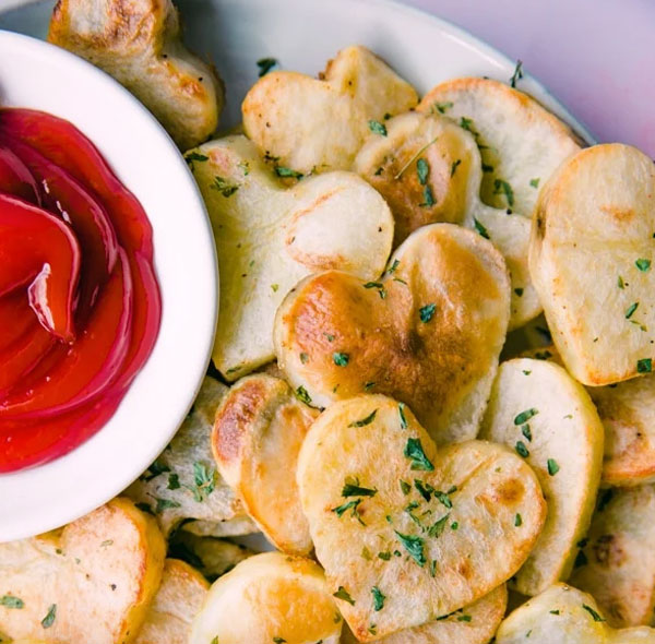 Heart shapped potatoes laid on a platter with savory tomato sauce.