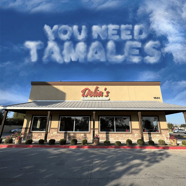 Letters that look like clouds in the sky that say, "You Need Tamales," over a mallen tamales restaurant.