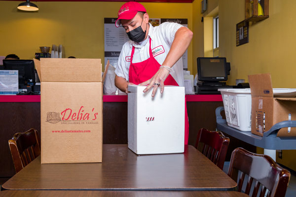 Male worker holding Delias boxes with the best tamles in San Antonio.